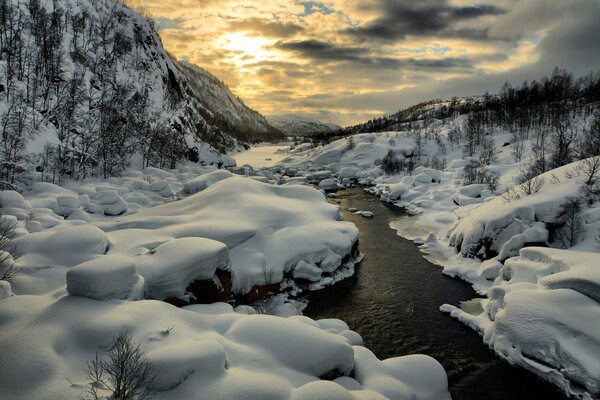 The river flows through mountains and snow