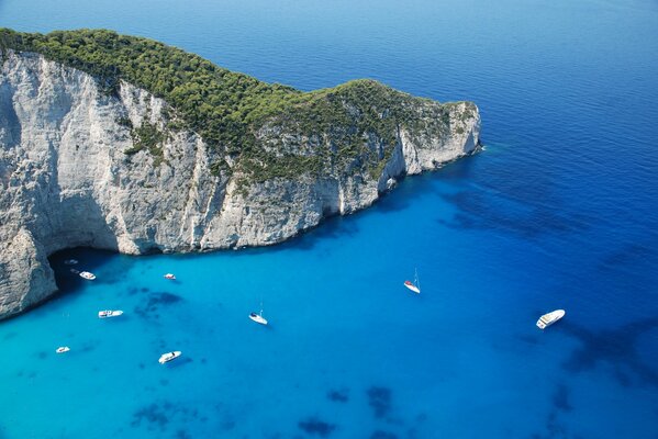 Yacht e barche a vela nell acqua blu del mare vicino alla montagna coperta di verde. Grecia