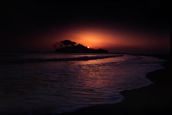 Tramonto cupo in riva al mare con ombre dall isolotto