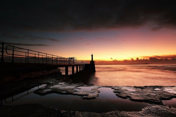 A bridge on the lake shore. Sunset