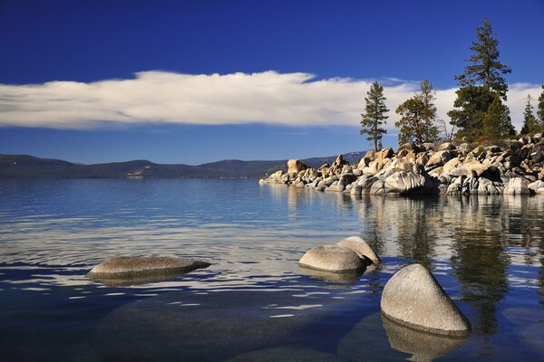 A lake with rocks and pine trees on the shore