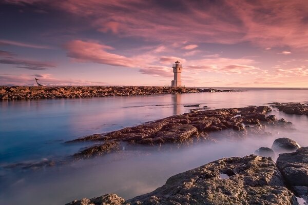 Phare dans la mer avec un beau coucher de soleil