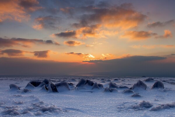 Pierres couvertes de neige, sur fond de ciel coucher de soleil