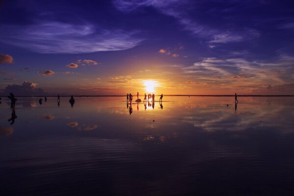 Gente en la distancia al atardecer junto al mar