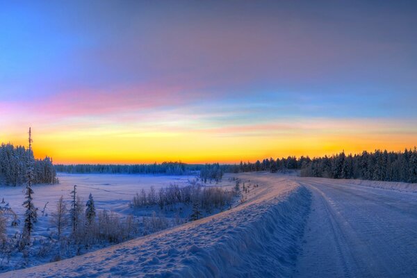 Winterstraße durch den Wald. Sonnenaufgang