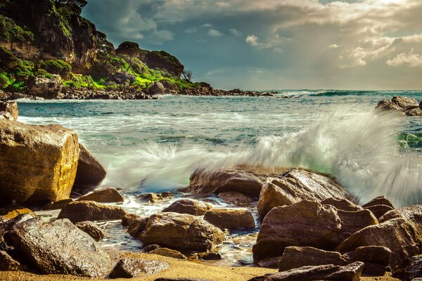 The waves of the ocean break on the rocky shore