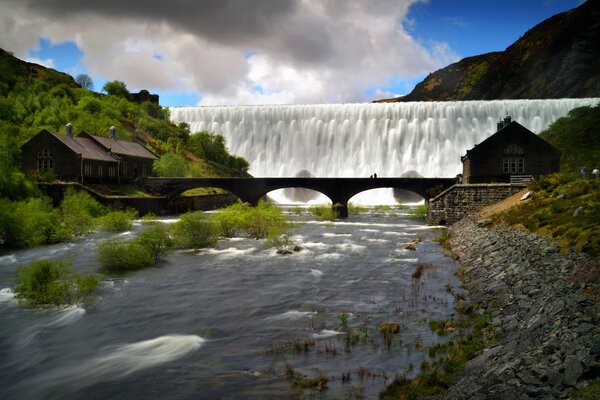 Schicker Wasserfall über einer Brücke in den Bergen