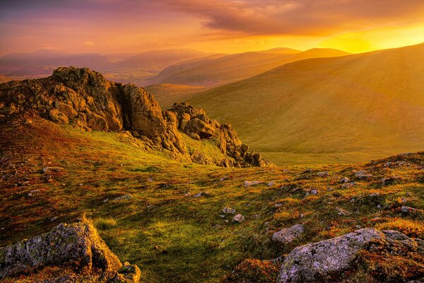 Rocce e colline di montagna illuminate dai raggi del sole in partenza