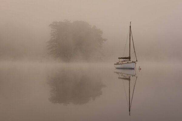 Яхта в тумане утреннего озера