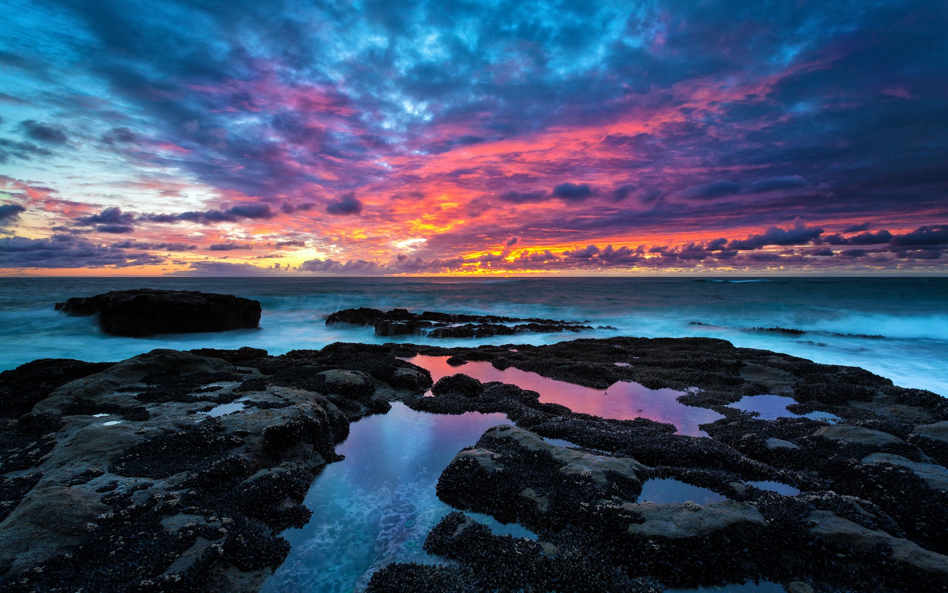 beach stones water sky clouds horizon