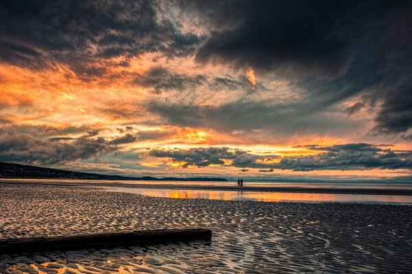 Dos se encuentran con la puesta de sol en la orilla del mar