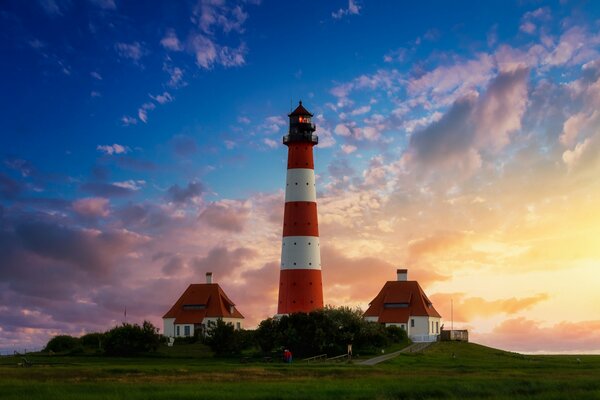 Phare et maisons sur fond de beau ciel coucher de soleil