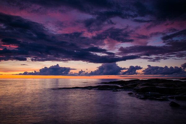 Mer calme et sans limite avec des nuages mauves