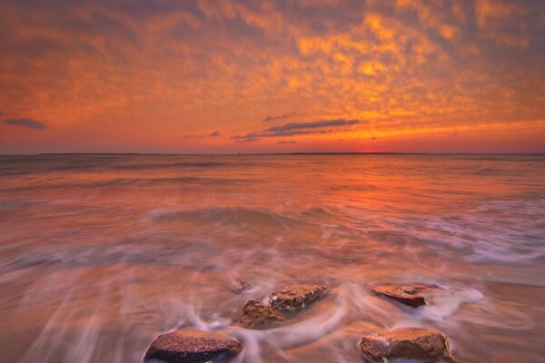 Яркий закат на море с камнями