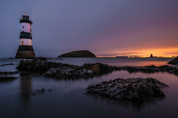 View from the shore to the lighthouse among the sea rocks