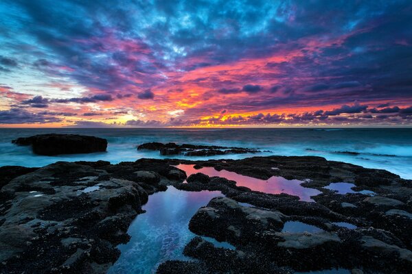 A rocky shore with a beautiful sky in the clouds