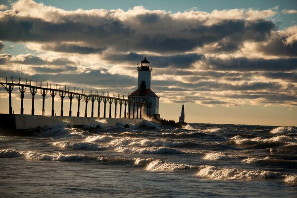 Lighthouse on the background of the waves of the sea