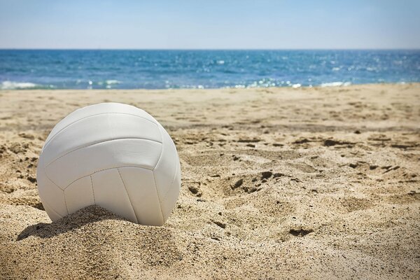 White volleyball ball on the sand