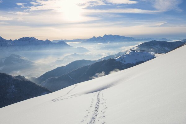Mountain snow massif from a height. Beautiful mountain landscape with motorcycle tracks on the white surface