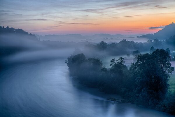 Im Nebel gehülltes Flussbett vor dem Hintergrund der Berge