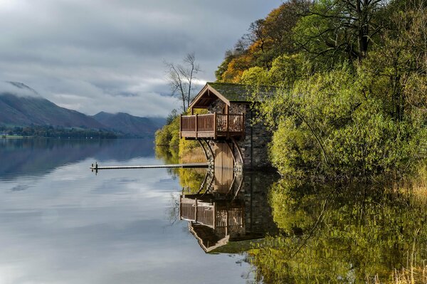 A house on the lake shore, mountains in the clouds