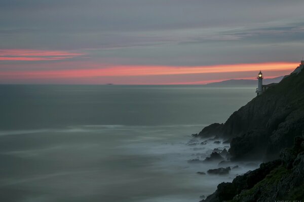 Lighthouse at sunset. Rocks and sea