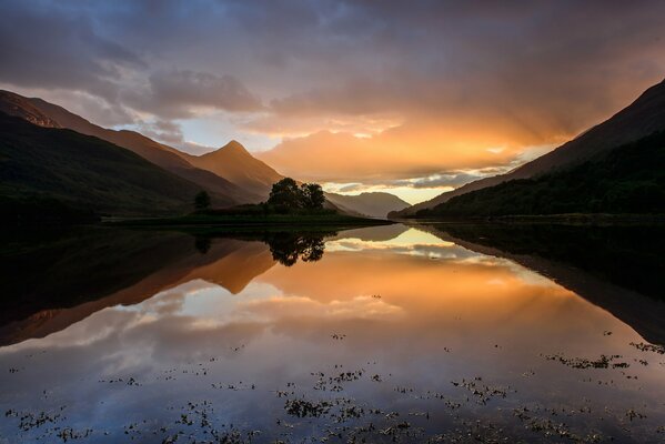 Puesta de sol de otoño en Escocia. El cielo se refleja en el agua y las montañas