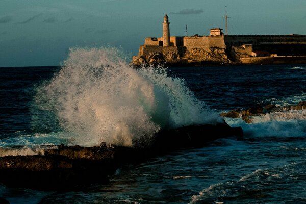 Splashing waves on the sea with a lighthouse in the distance