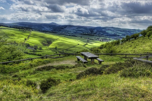 A green valley in the mountains. Benches on the hill