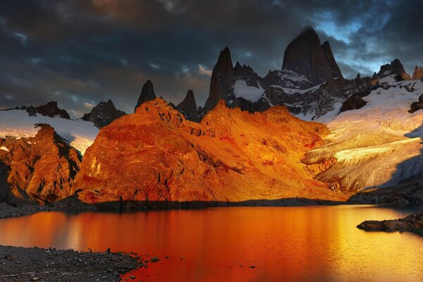 Amanecer en un lago rodeado de montañas cubiertas de nieve