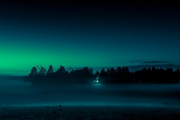 The field is wrapped in night fog, on the outskirts of which the flickering light of a lamp is visible