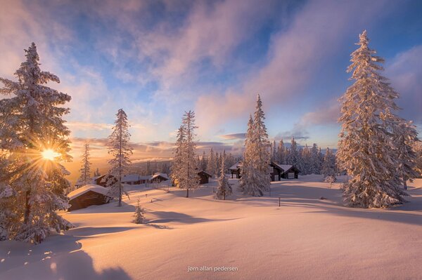 Hiver en Norvège, maisons cachées sous la neige et les rayons du soleil