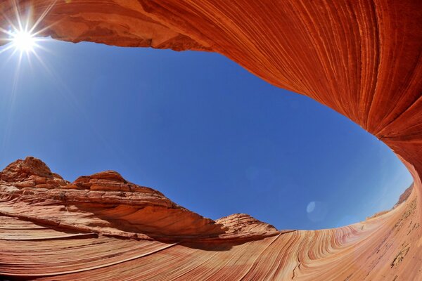 A través de la piedra arenisca se ve el cielo azul y el sol