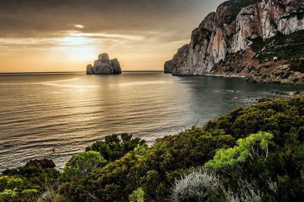 Roca en el mar en medio de la puesta de sol