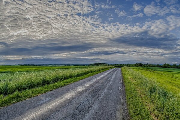 Straße in einem Feld unter den Wolken