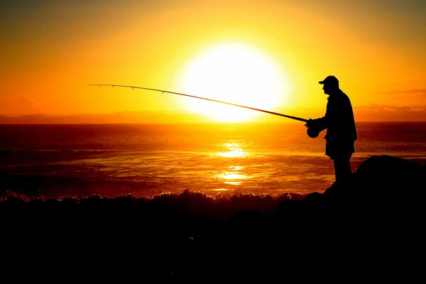 Silhouette of a fisherman against the background of a sea sunset