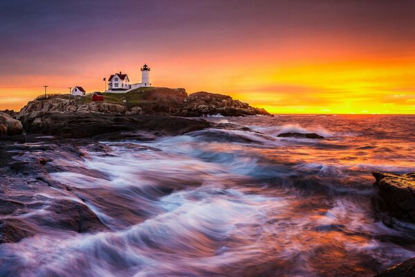 Amanecer en el mar. En las rocas hay un faro