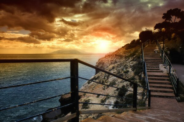 Stairs in the mountain by the sea at sunset