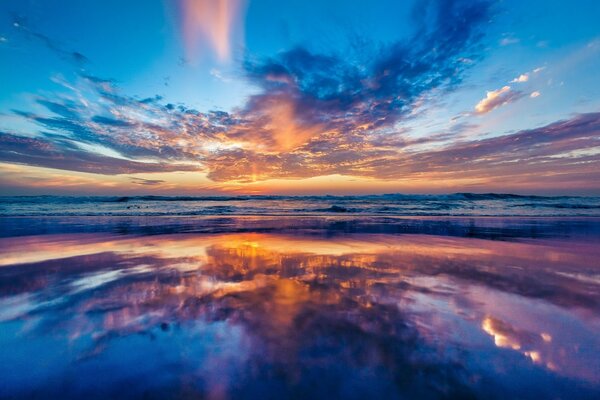 Sunrise on the ocean coast, reflected in the water