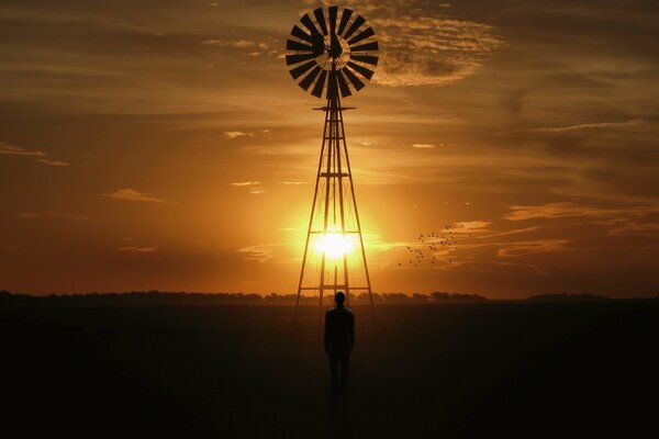 Mann und Windmühle auf Sonnenuntergang Himmel Hintergrund