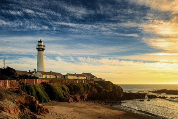 Sunrise on the shore of the sea beach with a lighthouse