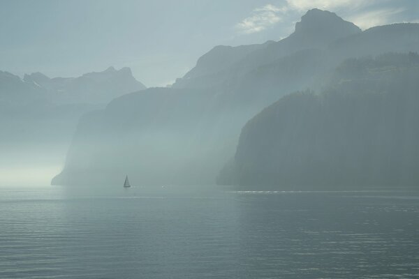 Foggy morning of a sailboat on the lake