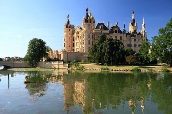 A large castle by the lake with trees