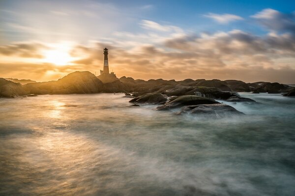 Lighthouse on the rocks in the misty distance