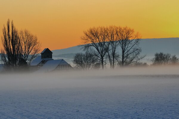 Schneebedeckte Ebene und ein Haus unter orangefarbenem Himmel