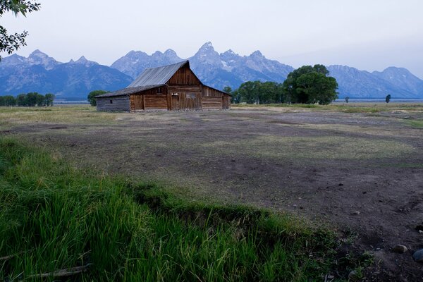 Casa en un campo en el fondo de las montañas