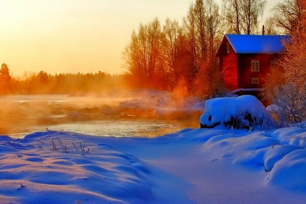 Steam over the river and snow on the background of sunset