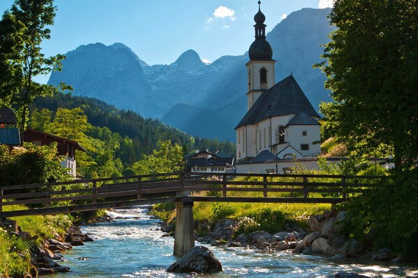 Brücke über den Fluss zwischen Bäumen, Bergen, Kirchen