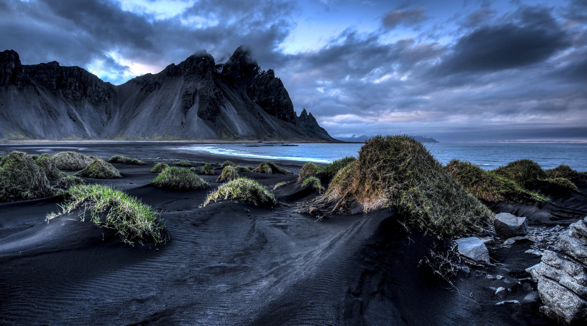 island vestrahorn stockksness berge schwarzer sand meer wolken gras ufer