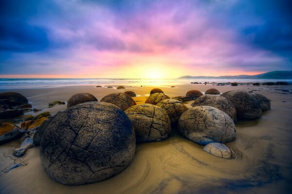 Las rocas que yacen en la arena se encuentran con el amanecer